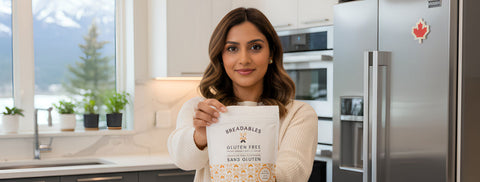 Woman in modern kitchen holding Breadables Gluten-Free flour, with mountain view, linking to gluten-free baking guide